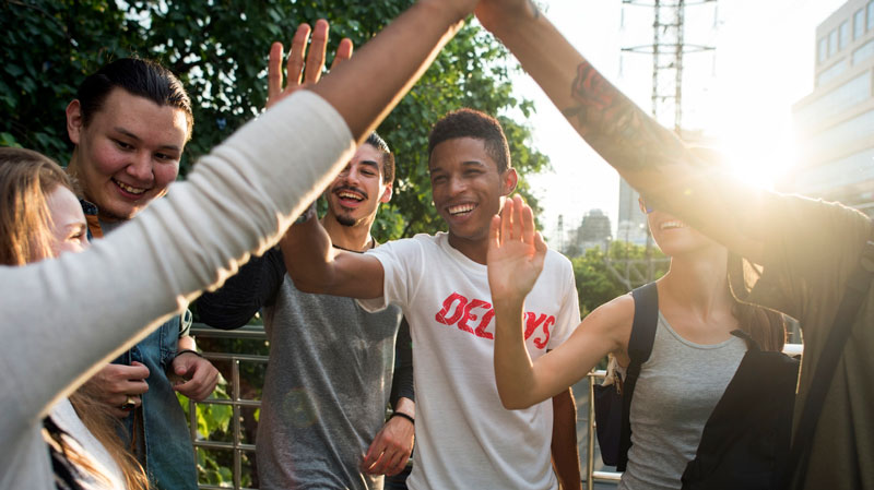 group of young adults outside high fiveing